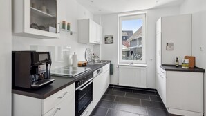 A compact kitchen with white cabinetry, a Siemens coffee machine, a built-in oven, and a window with a view of the neighborhood. - Cozy apartment in Bad Harzburg with WiFi (Bad Harzburg)