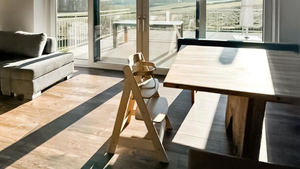 A modern living room with a wooden dining table, a sofa, and a chair. - Ferienhaus in Kapfenstein (Kapfenstein)