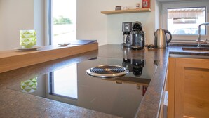A modern kitchen with a central island, a coffee maker, and a kettle on the countertop. - Ferienhaus in Kapfenstein (Kapfenstein)