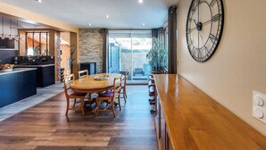 Une cuisine moderne avec un coin repas, comprenant une grande table en bois, des chaises et une horloge murale.