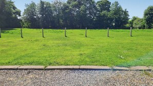 Un prato erboso con una recinzione e alberi sullo sfondo.
