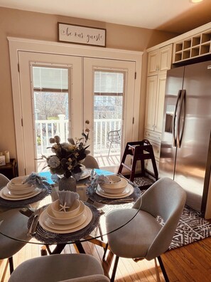 A dining area with a table set for four, a refrigerator, and a sign above the door reading "be our guest".