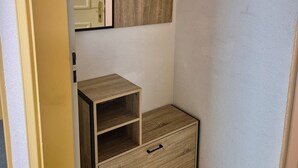 A corner room with a wooden cabinet, a mirror, and a small drawer unit.