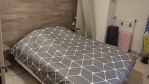 A bedroom with a bed, wooden headboard, and a ceiling light fixture.