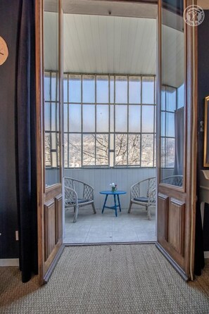 A room with a sliding glass door leading to a balcony with two wicker chairs and a small table. - LA Maison Rouge - Albertville (ALBERTVILLE)