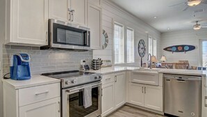 A modern kitchen with white cabinetry, a stainless steel stove, a microwave, and a dishwasher. - Breez In TC 10304 (Port Aransas)