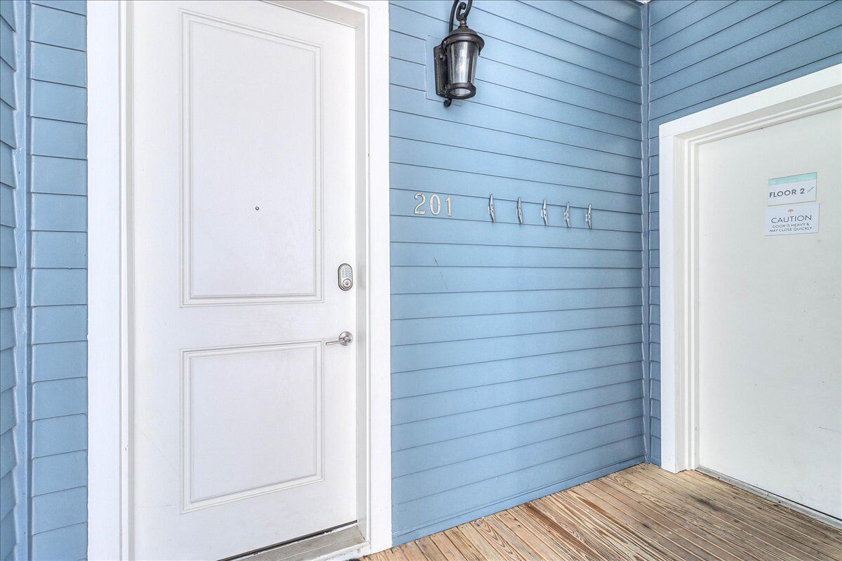 A hallway with a white door, a blue wall with the number 201, a metal light fixture, and a caution sign on the adjacent door.