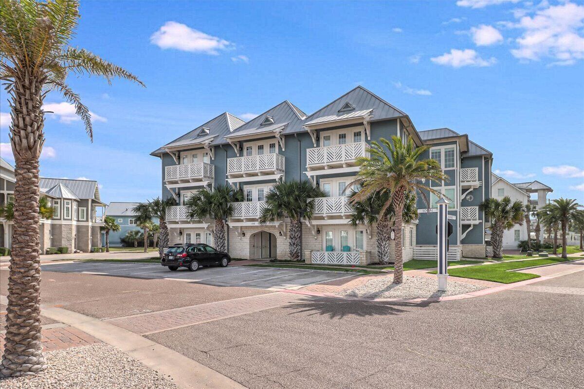 A multi-story hotel with balconies, palm trees, and a clear sky.