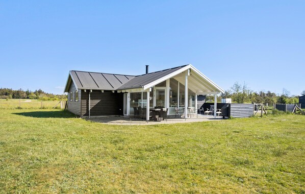 Une maison de plain-pied dotée d’un patio couvert, d’une cheminée et d’une cour clôturée.