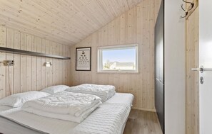Une chambre avec un lit superposé, des murs en bois, une fenêtre et une porte.