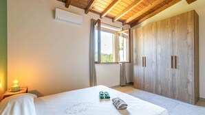 Een slaapkamer met houten plafond, raam, kledingkast en bedlamp.