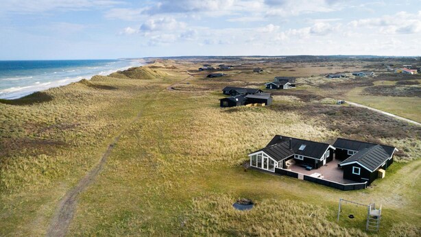 Una propiedad costera con varias casas, una playa de arena y cielo despejado.