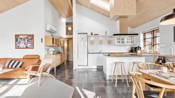 A modern kitchen with white cabinets, a central island, and a dining area with wooden chairs and a table. - Gorgeous home in Ejstrupholm with WiFi (Ejstrupholm)