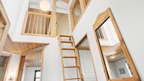 A multi-level interior with wooden beams, a central staircase, and multiple windows. - Gorgeous home in Ejstrupholm with WiFi (Ejstrupholm)