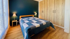 Ein Schlafzimmer mit einem hölzernen Bett, zwei Nachttischlampen, einer dunkelblauen Wand und einem Holzschrank.