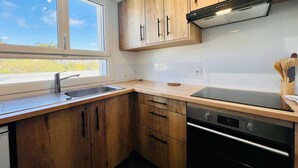 Eine moderne Küche mit Holzausbau, einer Edelstahlspüle und einem eingebauten Backofen.