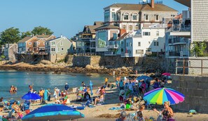 Una playa con gente, sombrillas y edificios al fondo.