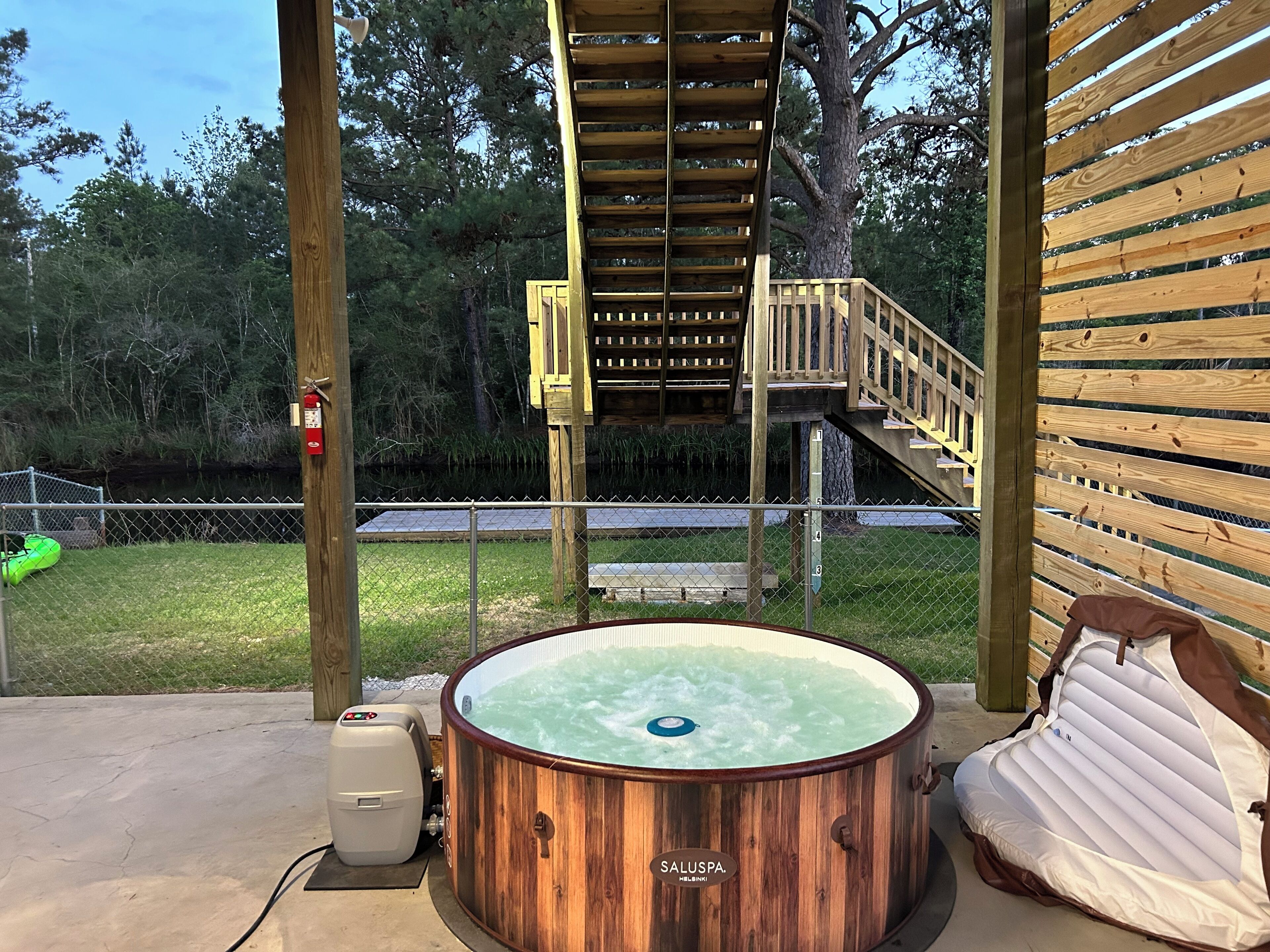 A wooden hot tub with a control panel, a wooden deck, and a wooden staircase leading to a deck area.