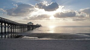 Eine Pier, die sich über ruhiges Wasser erstreckt, mit einem klaren Himmel und untergehender oder aufgehender Sonne.