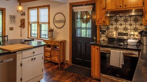 A kitchen with wooden cabinets, a black oven, and a stainless steel range hood. - Serendipity on the river  (Suches)