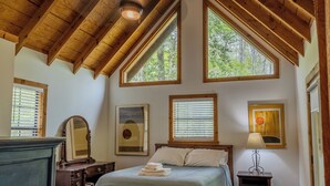A bedroom with a wooden ceiling, large windows, a bed, a dresser, and a nightstand. - Serendipity on the river  (Suches)