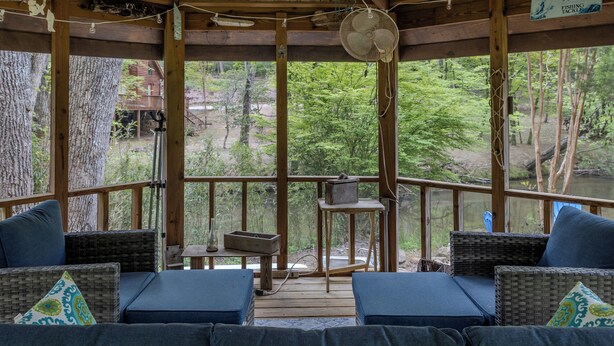 A wooden deck with wicker furniture and a fan, overlooking a forested area. - Serendipity on the river  (Suches)