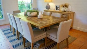 A dining area with a wooden table, six chairs, a decorative lamp, and a plant on the table. - Stunning Highlands Manor-Accommodates 2-12 people  (Mittagong)