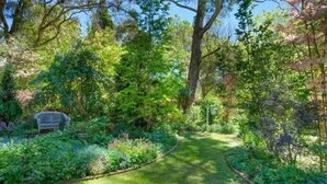 A garden with a paved path, a bench, and various plants. - Stunning Highlands Manor-Accommodates 2-12 people  (Mittagong)