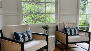 A room with two armchairs, a small side table, and a window with a view of greenery. - Stunning Highlands Manor-Accommodates 2-12 people  (Mittagong)