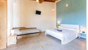 Een slaapkamer met een bed, een bankje, een televisie en een houten plafond.