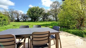 Une table et des chaises installées à l’extérieur, avec vue sur les arbres et l’herbe.