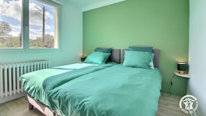 Een slaapkamer met een bed, twee nachtkastjes, een raam en een radiator.