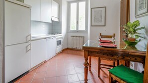 A kitchen with white cabinets, a stove, a dining table with chairs, and a window. - Nice apartment in Firenze with WiFi (Firenze)