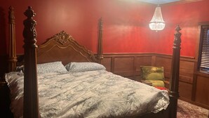 A four-poster bed with a floral bedspread in a room with red walls and a chandelier. - Fisherman's Retreat! (Burwell)