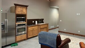 A modern kitchen with built-in appliances, wooden cabinets, and a patterned rug. - Fisherman's Retreat! (Burwell)