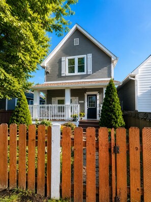 A two-story house with a porch, a front door, and a small front yard.