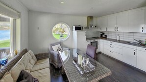 Una cocina moderna con armarios blancos, un comedor con mesa redonda y vistas al exterior por una ventana.