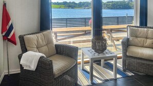 Una habitación acogedora con sillones de mimbre, una mesita y vistas a un lago y un muelle.