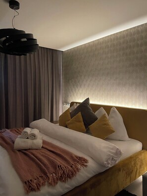 Une chambre d’hôtel avec un lit, une tête de lit, un mur orné d’un motif texturé et un luminaire suspendu.