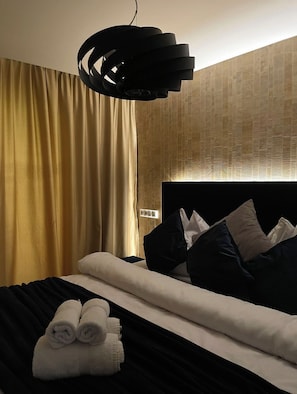 A hotel room with a bed, a headboard, a wall-mounted light fixture, and a curtain. - Luxury apartment with sauna - family and pet friendly (Vysoké Tatry)