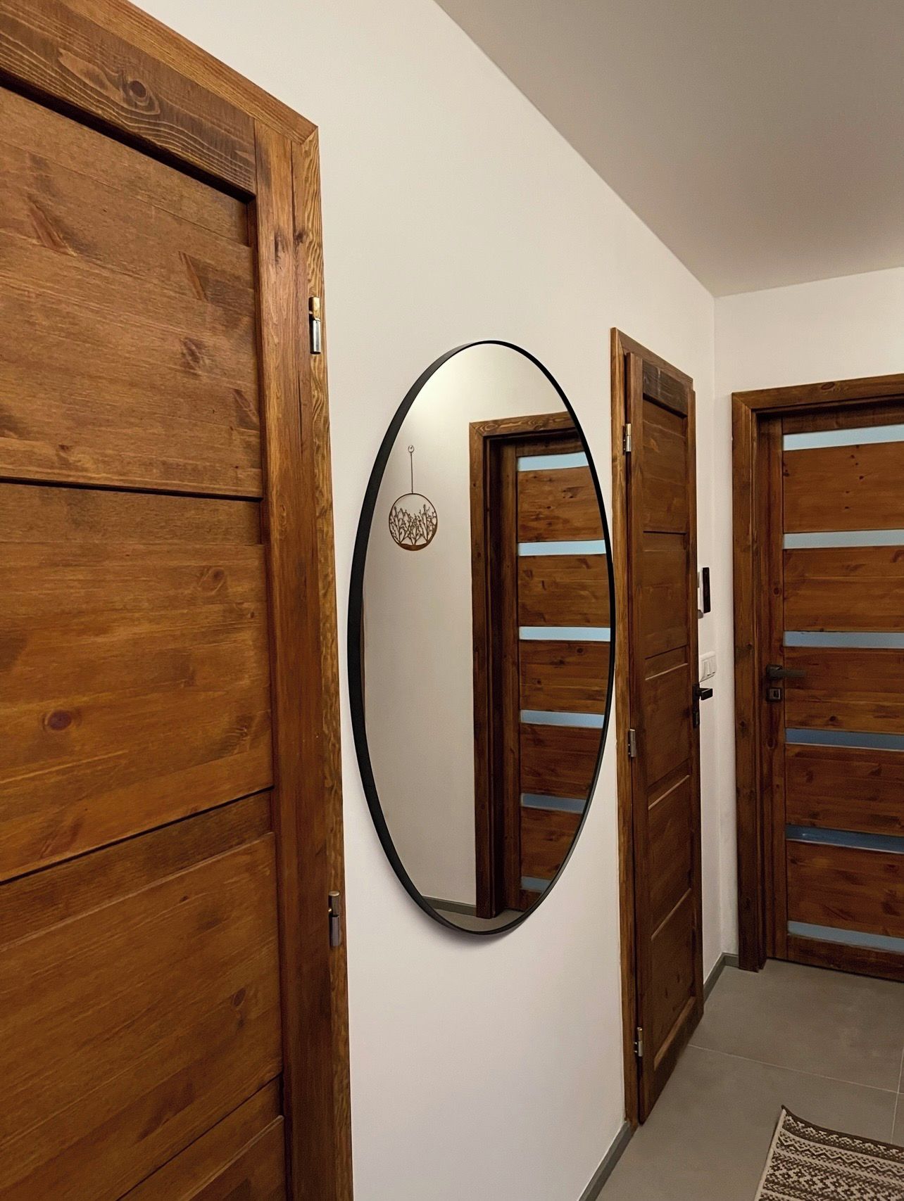 Een gang met houten deuren en een ronde spiegel aan de muur.