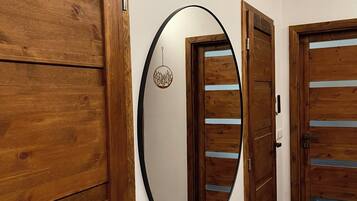 Een gang met houten deuren en een ronde spiegel aan de muur.