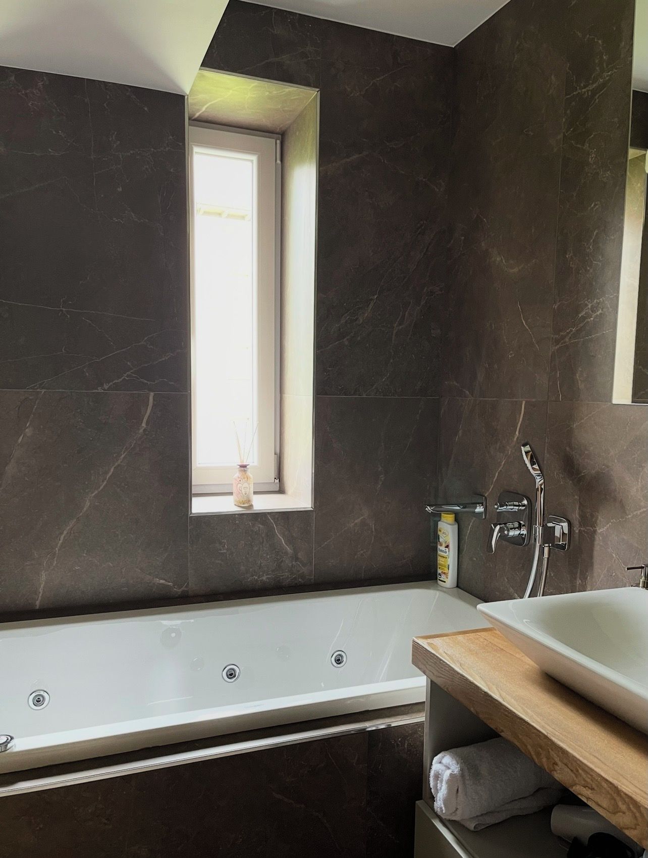 A modern bathroom with a bathtub, a window, and a shower area.