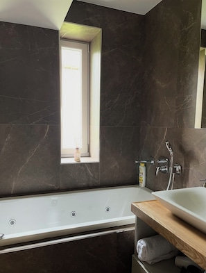 A modern bathroom with a bathtub, a window, and a shower area. - Luxury apartment with sauna - family and pet friendly (Vysoké Tatry)