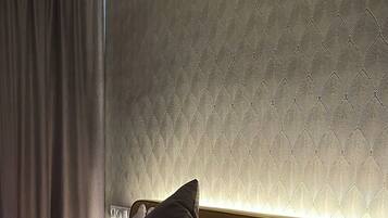 A hotel room with a bed, pillows, and a wall with a textured pattern.