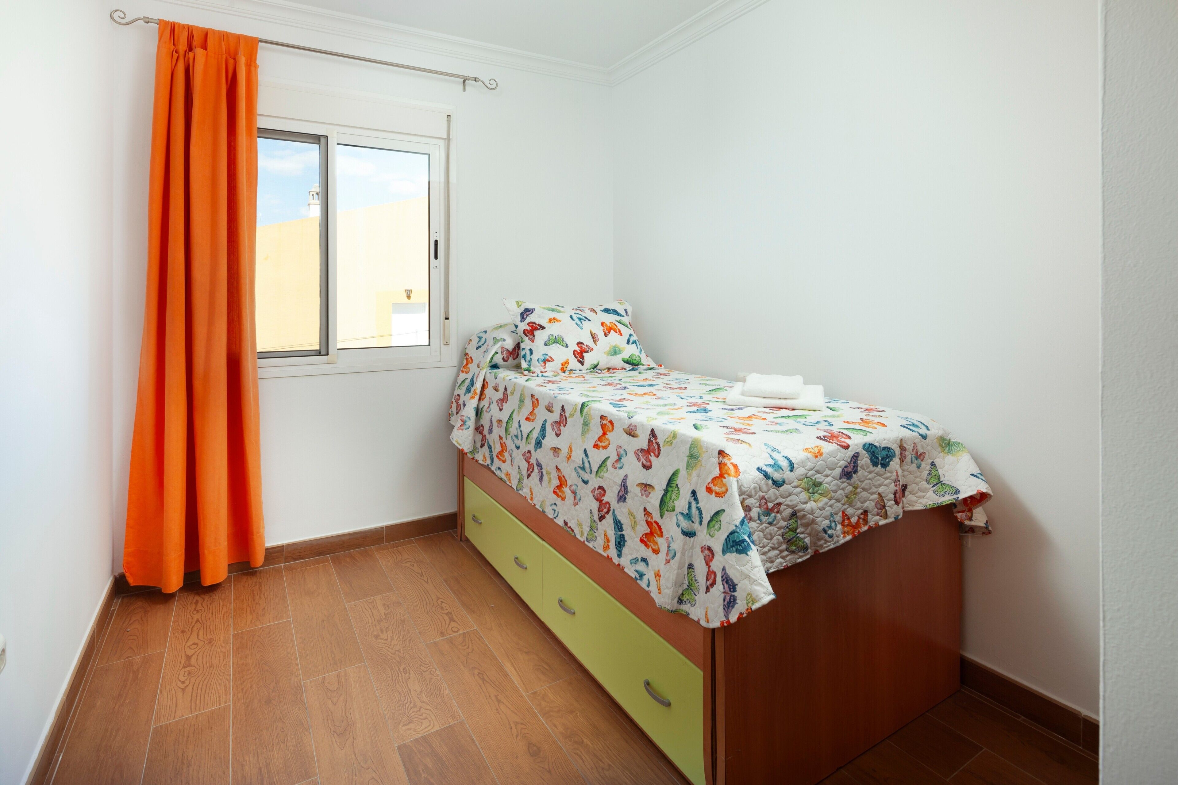 A bedroom with a bed, a window, and a curtain.