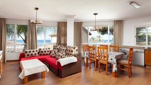 Un salon comprenant un canapé, une table à manger, des chaises et une vue sur la mer.