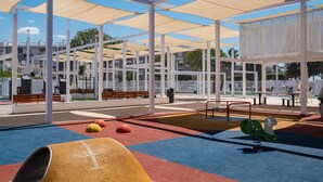 Un espace extérieur abrité comprenant une aire de jeux, des bancs et une clôture.