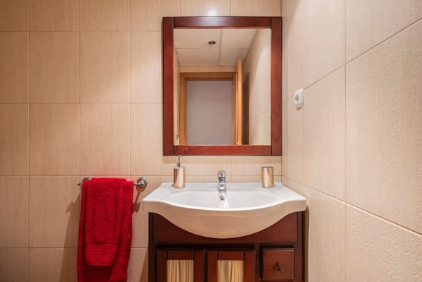 Ein Badezimmer mit Waschbecken, Spiegel und rotem Handtuch.