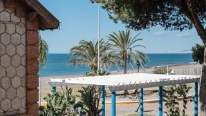 Une vue sur la côte, avec une pergola blanche, des palmiers et un ciel bleu azur.